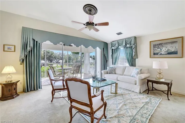 Formal living room with ceiling fan and vaulted ceiling with sliders opening to the lanai.