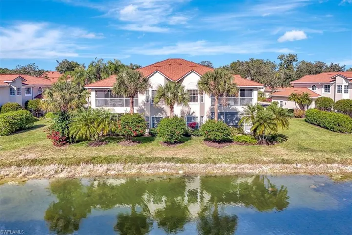 View of the back of home featuring a water view, lawn and a balcony.