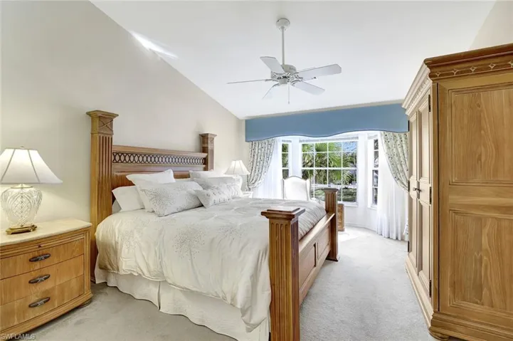 Sunlit primary bedroom featuring lofted ceiling, ceiling fan and gorgeous lake view.
