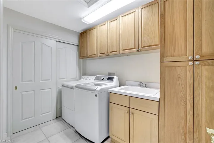 Laundry room with custom cabinet space, washing machine and dryer and sink.