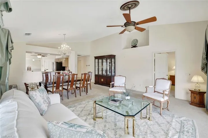 Formal living room with a ceiling fan, a chandelier and high vaulted ceiling.