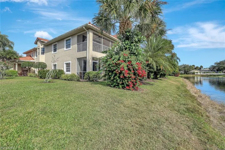 View of property exterior featuring a lanai/balcony, lawn and a water view