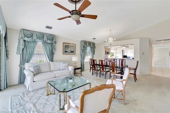 Formal living area featuring a ceiling fan, a chandelier, vaulted ceiling, and plenty of natural light.
