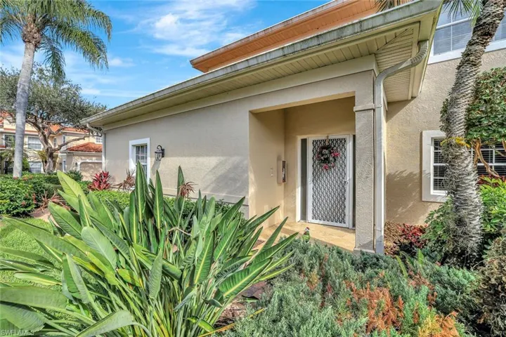 Doorway to property featuring plush landscaping.