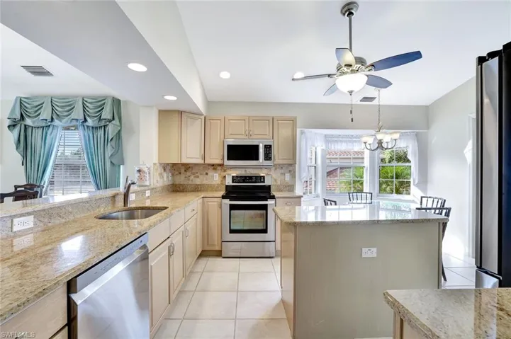 Kitchen with stainless steel appliances , granite counters, recessed lighting, light tile patterned flooring, and island.