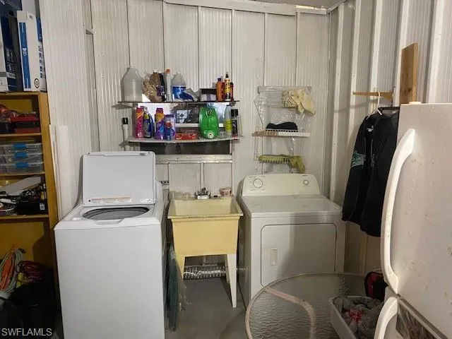 Laundry room with concrete flooring, washer and clothes dryer, and metal wall