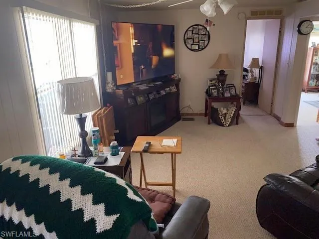 Living area with light carpet and ceiling fan