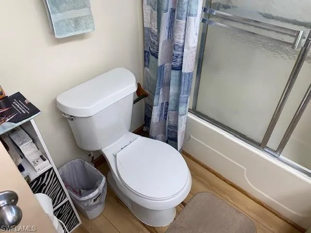 Full bathroom featuring bath / shower combo with glass door and toilet