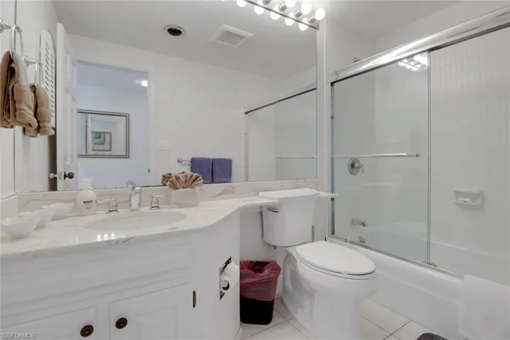Bathroom with tile patterned flooring, toilet, vanity, and combined bath / shower with glass door