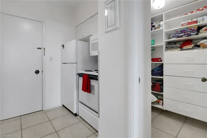 Kitchen with white appliances, white cabinetry, light tile patterned floors, and light countertops