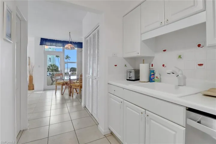 Kitchen featuring stainless steel dishwasher, a sink, decorative backsplash, white cabinets, and light tile patterned flooring