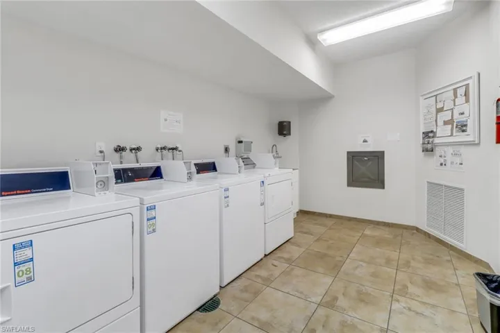 Community laundry room with washing machine and clothes dryer, light tile patterned floors, and baseboards