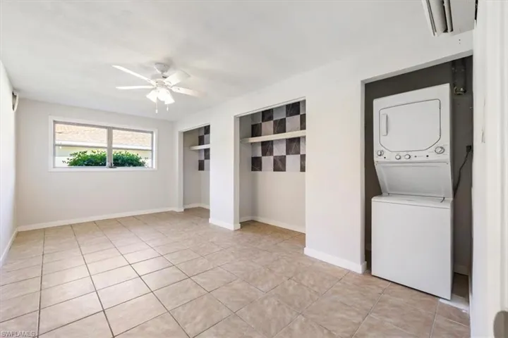 Laundry room with stacked washer / drying machine, light tile patterned floors, and ceiling fan