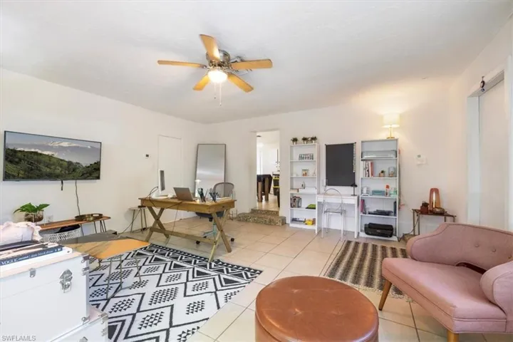 Living area with light tile patterned floors, ceiling fan, and an office area