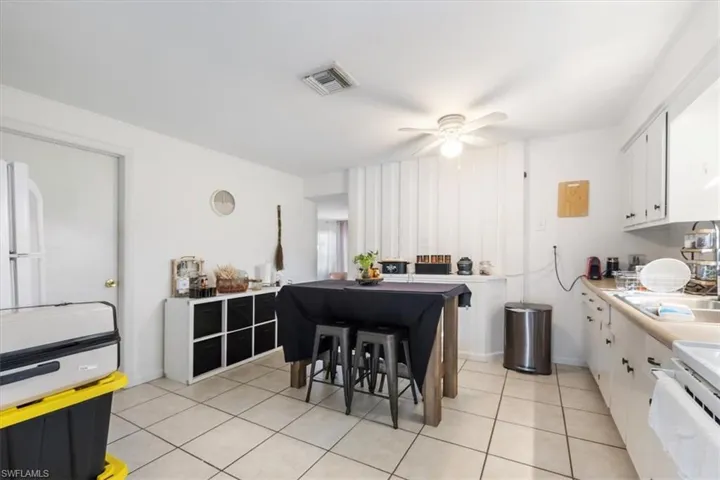 Kitchen featuring white cabinets, light tile patterned floors, light countertops, stove, and freestanding refrigerator