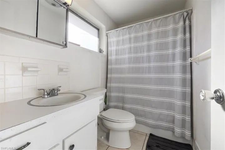Full bathroom featuring vanity, light tile patterned floors, and backsplash