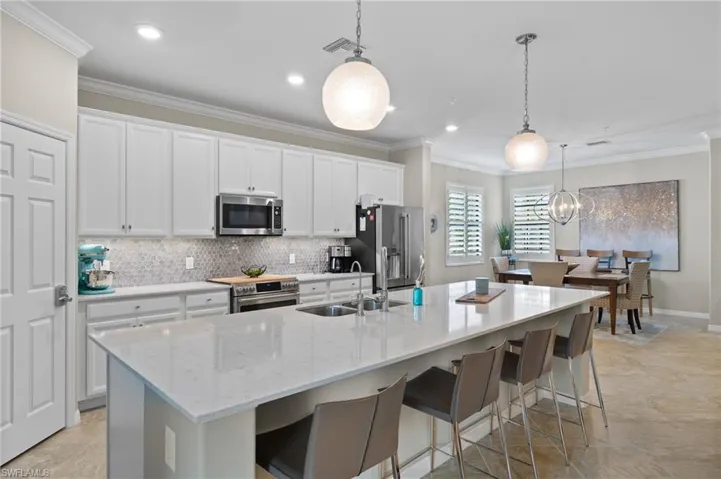 Kitchen with sink, a center island with sink, light tile patterned flooring, and GE Cafe Series appliances.