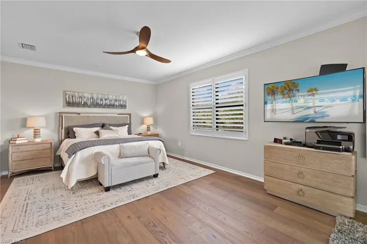 Bedroom featuring ceiling fan, dark hardwood / wood-style floors, and crown molding and walk out access to screened lanai