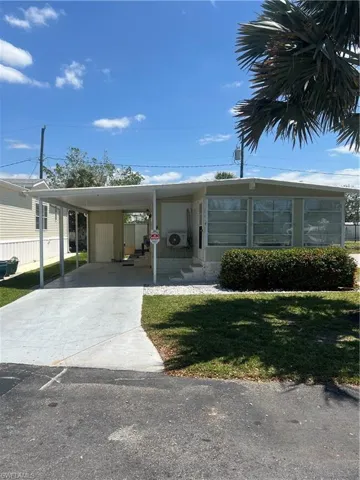 View of front facade featuring a front yard, concrete driveway, and an attached carport