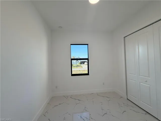 Unfurnished bedroom featuring light marble finish flooring and a closet