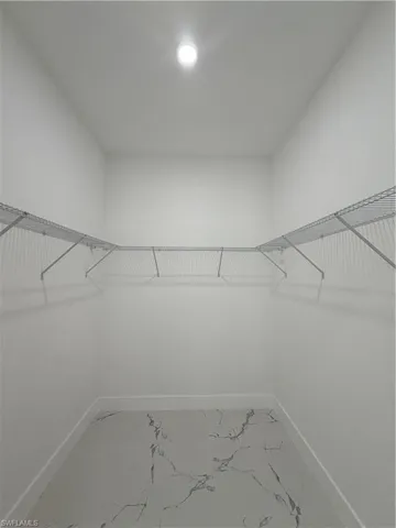 Walk in closet with light marble finish floors