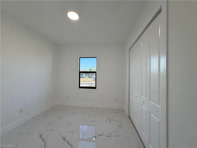 Unfurnished bedroom with a closet and light marble finish floors