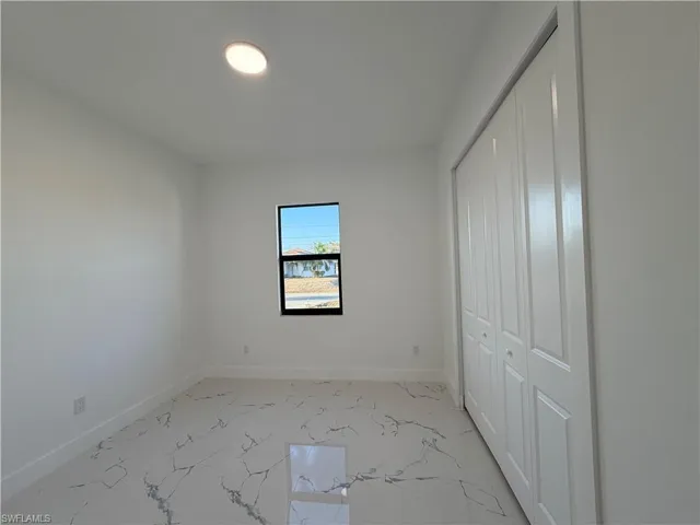 Unfurnished bedroom featuring a closet and light marble finish floors