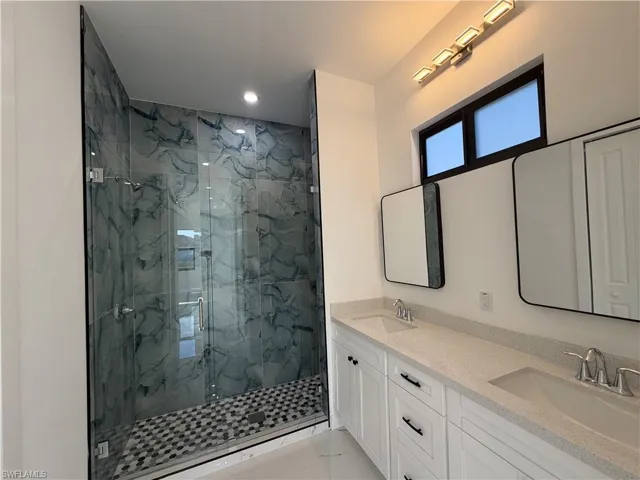 Full bath featuring double vanity, a marble finish shower, and recessed lighting