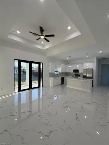 Unfurnished living room with ceiling fan, french doors, recessed lighting, and a raised ceiling