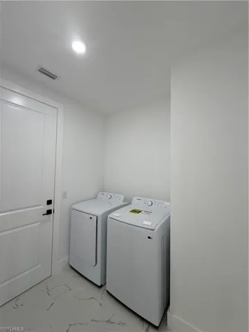 Laundry area with light marble finish floors, washing machine and clothes dryer, and recessed lighting