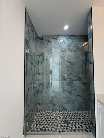 Full bathroom featuring a marble finish shower, vanity, and recessed lighting