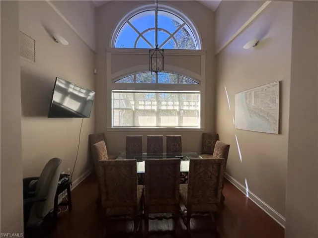 Dining area featuring dark wood-style flooring, visible vents, a towering ceiling, and baseboards