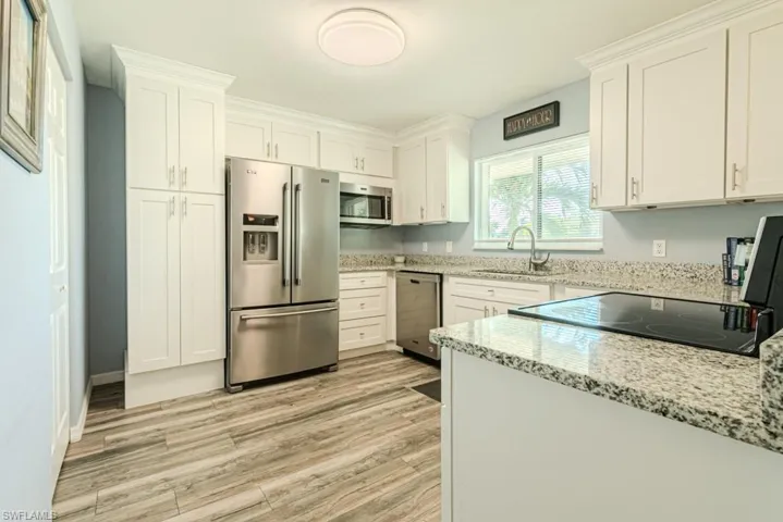 Kitchen with sink, appliances with stainless steel finishes, white cabinetry, and light hardwood / wood-style floors