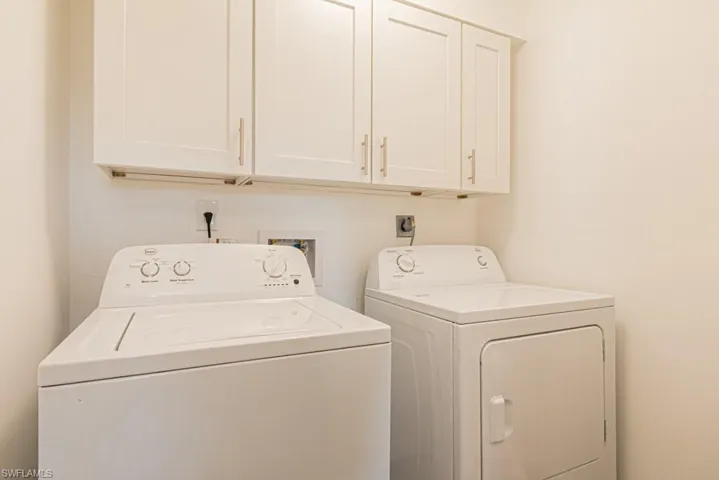 Washroom featuring separate washer and dryer and cabinets