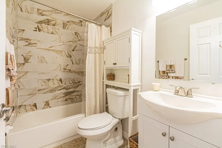 Full bathroom with vanity, shower / bath combo with shower curtain, toilet, and tile patterned floors