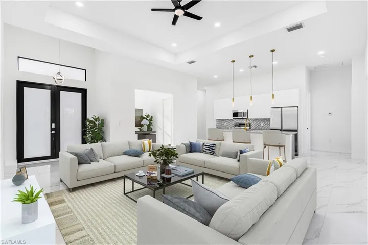 Living room with ceiling fan, a raised ceiling, light marble finish floors, and recessed lighting