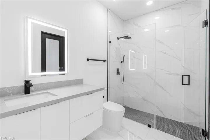 Full bath featuring vanity, a marble finish shower, and recessed lighting