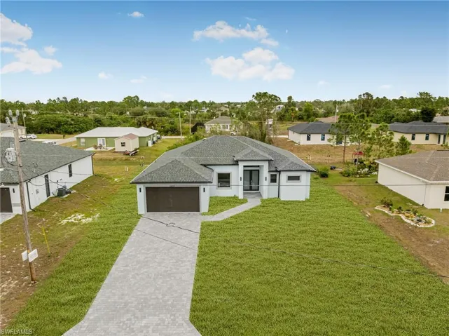View of front facade featuring a residential view, driveway, a garage, and a front lawn