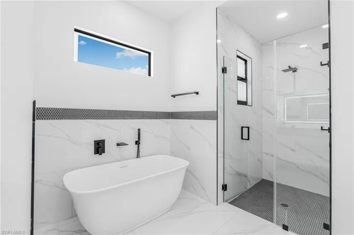 Bathroom featuring a marble finish shower, plenty of natural light, a soaking tub, marble tiled flooring, and recessed lighting