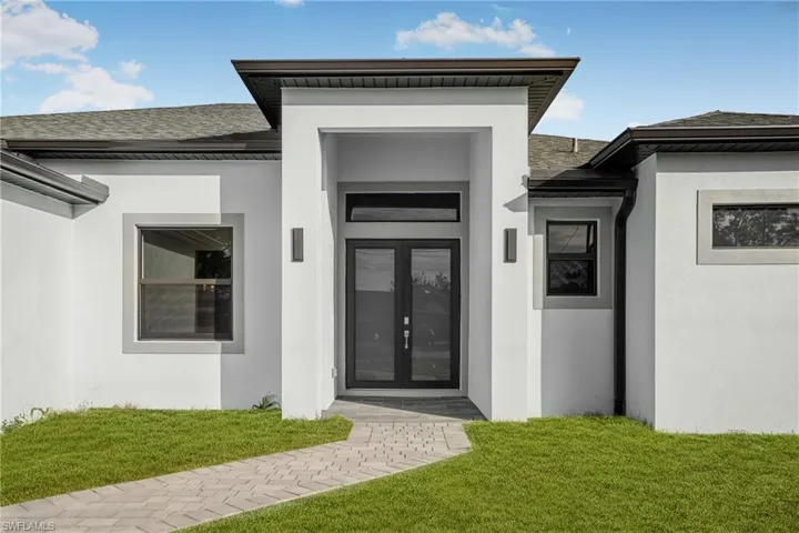 Entrance to property featuring a yard, french doors, stucco siding, and roof with shingles