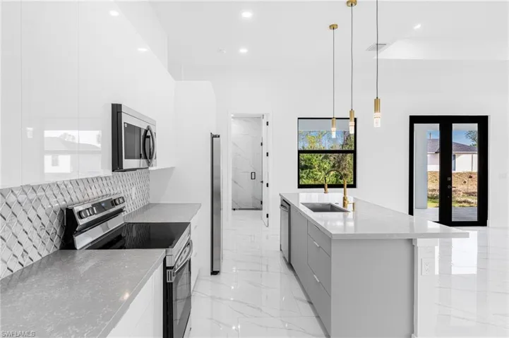 Kitchen featuring stainless steel appliances, french doors, modern cabinets, a center island with sink, and white cabinets