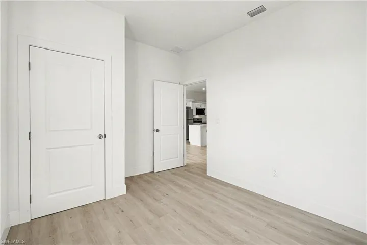 Unfurnished bedroom with light wood-style flooring and freestanding refrigerator