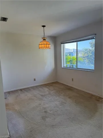 Empty room with baseboards, visible vents, and carpet