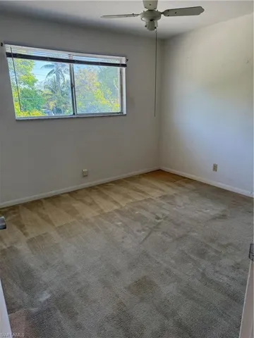 Unfurnished room featuring a ceiling fan, baseboards, and carpet flooring