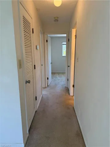 Corridor with light carpet and baseboards