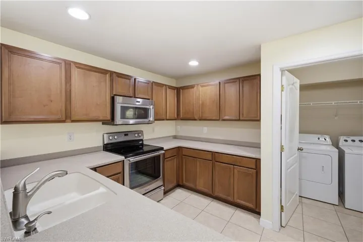 Kitchen featuring wood cabinetry, light-toned countertops, and stainless steel appliances including a built-in microwave and range