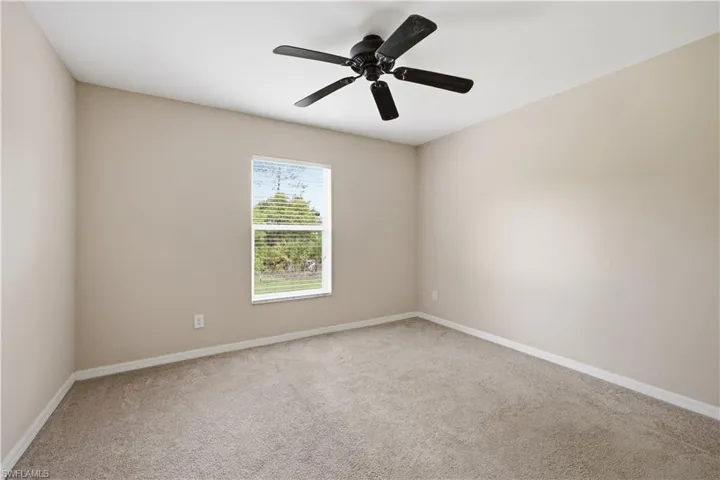 Neutral-toned interior with carpet flooring and a single window featuring horizontal blinds