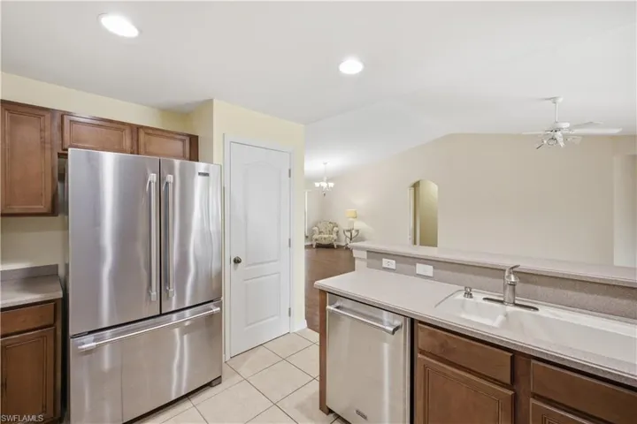 Kitchen featuring stainless steel French door refrigerator, wood-finish cabinetry, and a double basin sink
