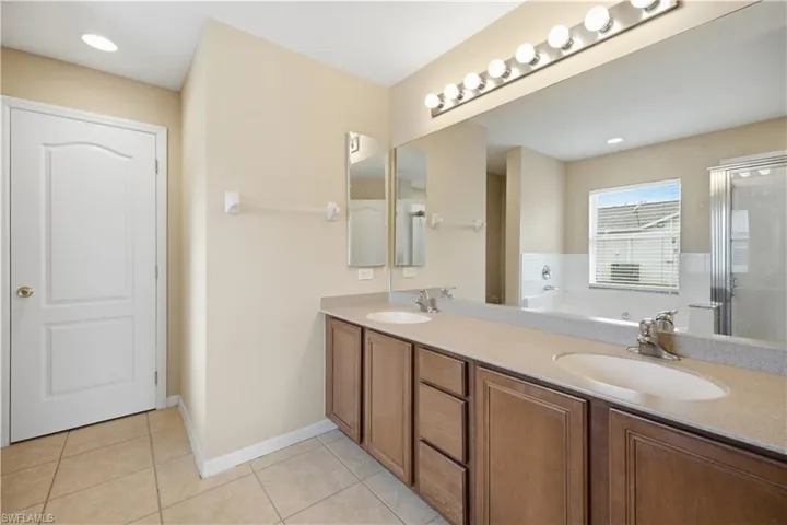 Bathroom featuring a dual vanity with undermount sinks, a built-in bathtub, and a separate glass-enclosed shower
