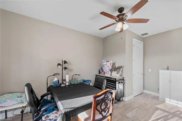Home office with light wood-type flooring and a ceiling fan